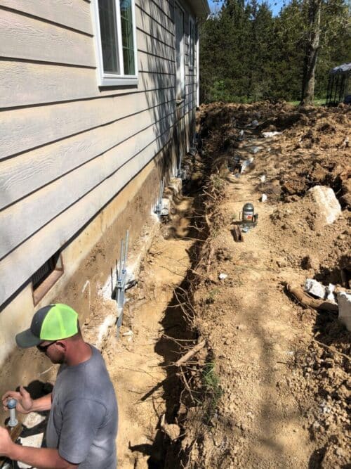 A Missouri Foundation & Foam expert helps with installing helical piers on a home to help with the foundation.