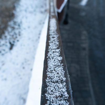 Vertical selective focus shot of snow in a railing in a Sibiu, Romania
